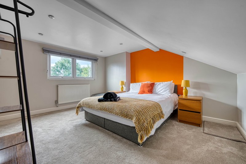 Modern bedroom with orange headboard, double bed, wooden nightstands and large window