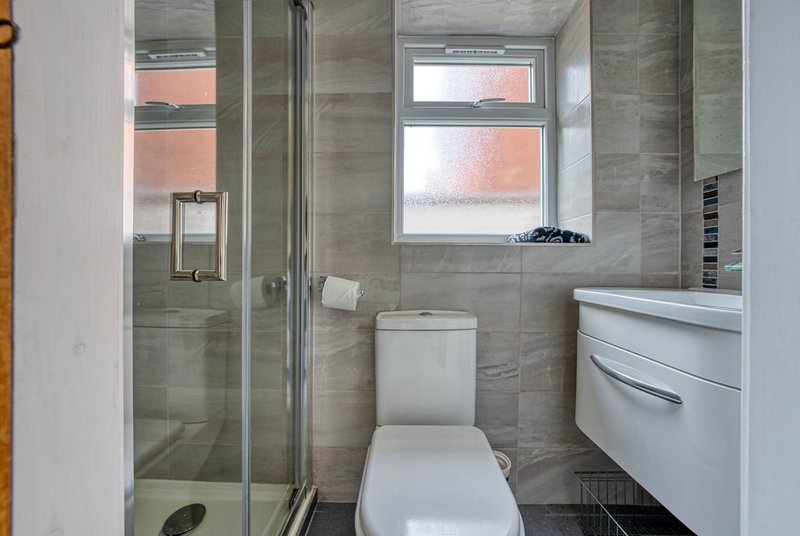 Modern bathroom with walk-in shower, toilet, vanity sink and window