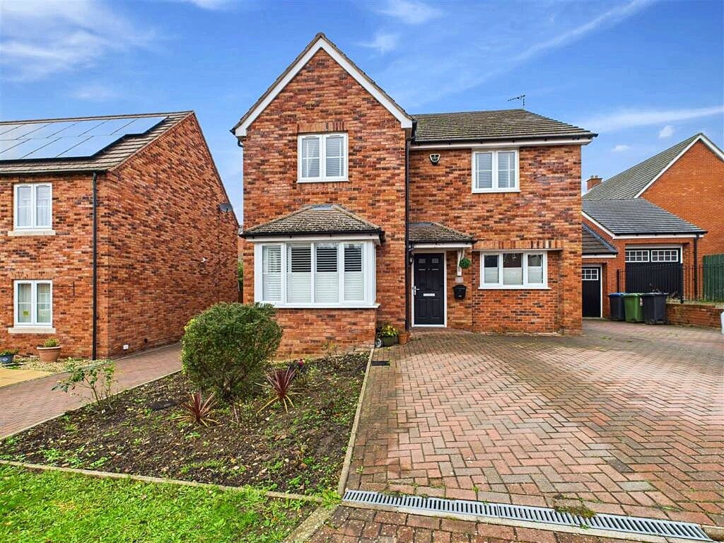 Brick detached house with driveway and front garden.