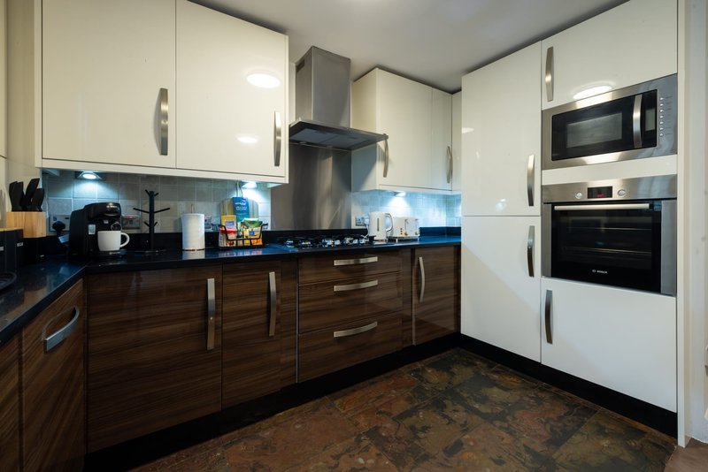 Modern kitchen with white and dark wood cabinets, stainless steel appliances, blue backsplash and countertop