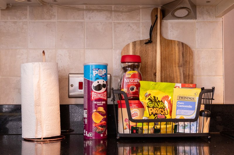 Kitchen counter with paper towel holder, coffee, tea, and condiment bottles arranged on shelf
