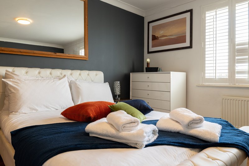 Bedroom with double bed, colorful pillows, folded towels, and modern decor