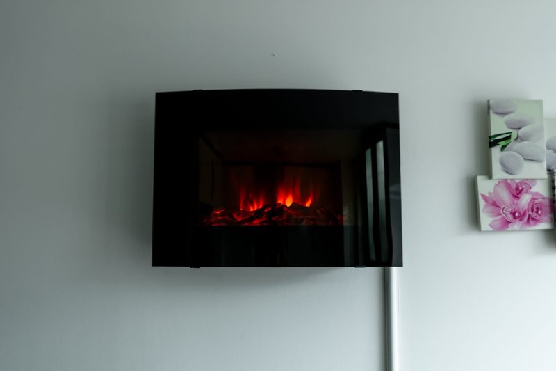 Wall-mounted electric fireplace with glowing red flames and decorative floral artwork