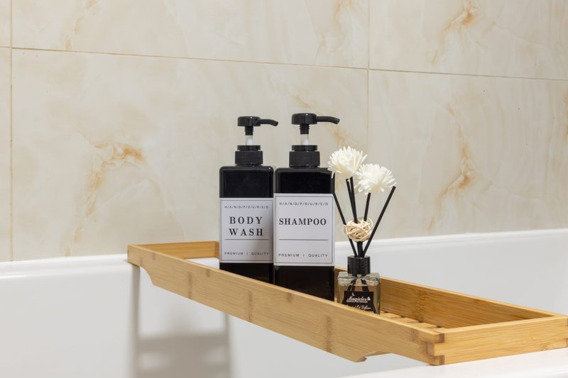 Bathroom bathtub caddy with toiletries, soap dispenser, and decorative reed diffuser