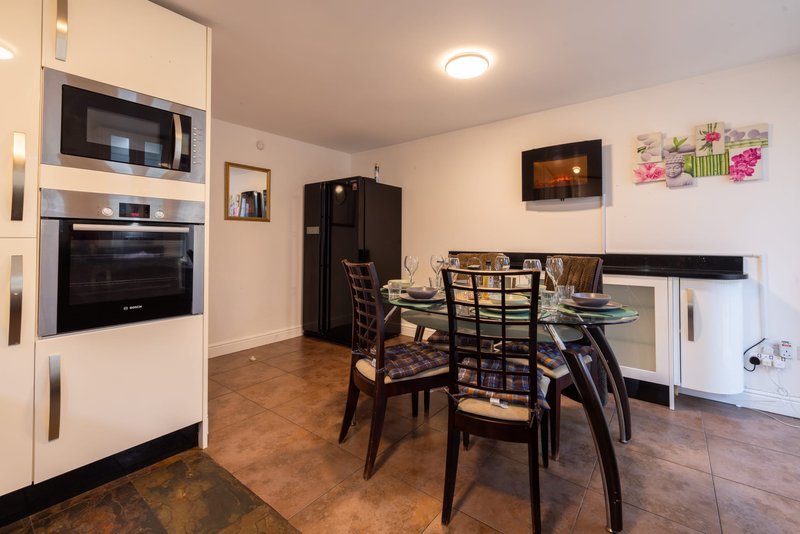 Modern kitchen-diner with stainless steel appliances, dining table, wooden flooring and wall art