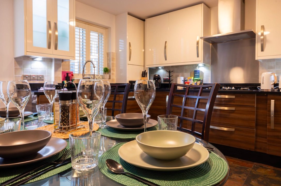 Modern kitchen and dining area with place settings, wine glasses, and stainless steel appliances