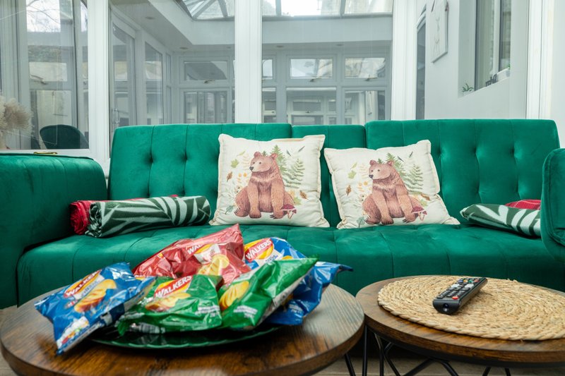 Bright living room with emerald green sofa, decorative cushions, wooden coffee table and snacks