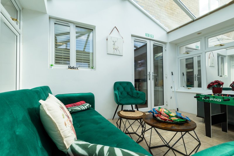 Bright modern living room with green sofa, armchair, glass doors and skylights