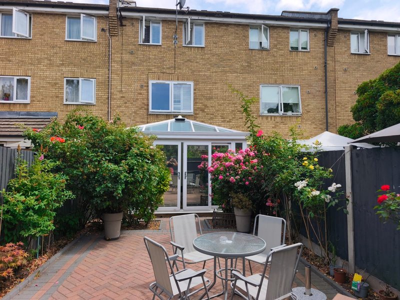 Brick townhouse with patio garden, outdoor dining table, potted plants and flowers