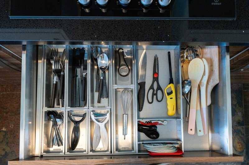 Kitchen drawer organizer with cutlery, utensils, tools and household items neatly arranged