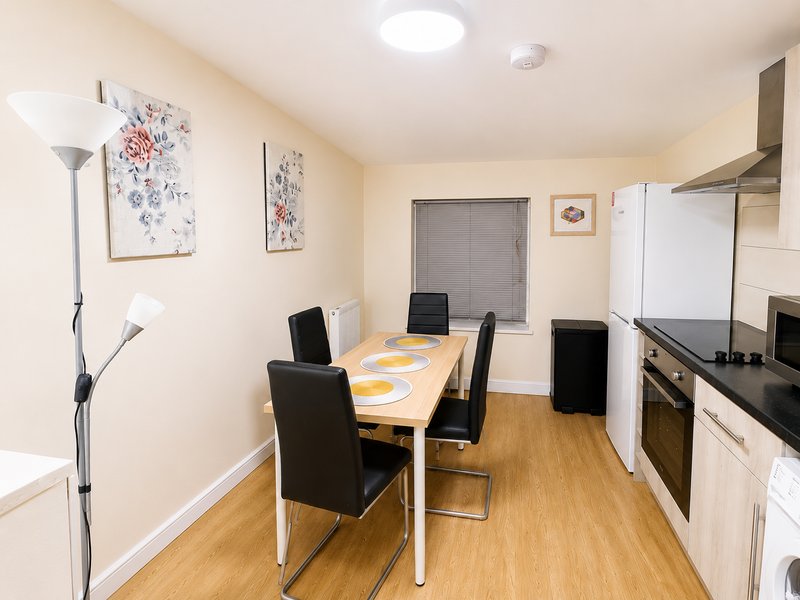 Kitchen-diner with wooden table, black chairs, cream cabinetry and stainless steel appliances