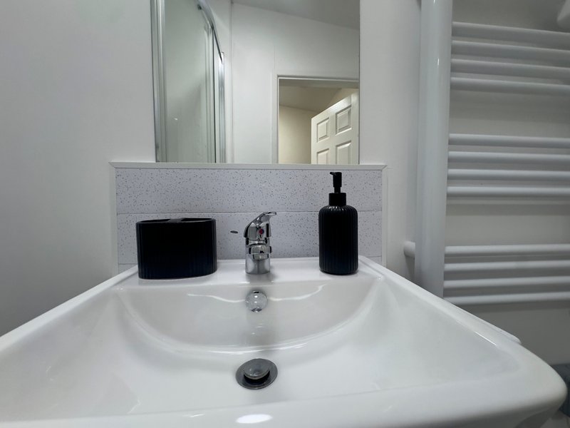 Modern bathroom sink with mirror, faucet, and black toiletry dispensers