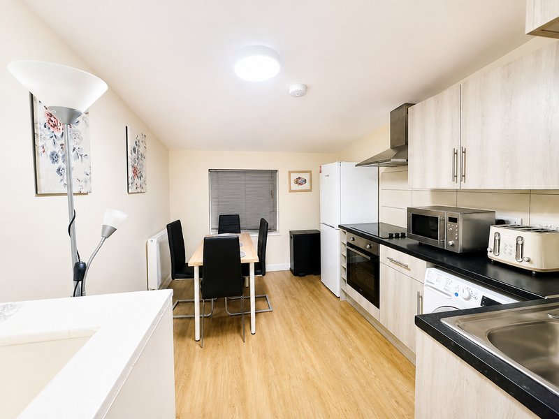 Modern kitchen with white cabinetry, black countertop, dining table and black chairs