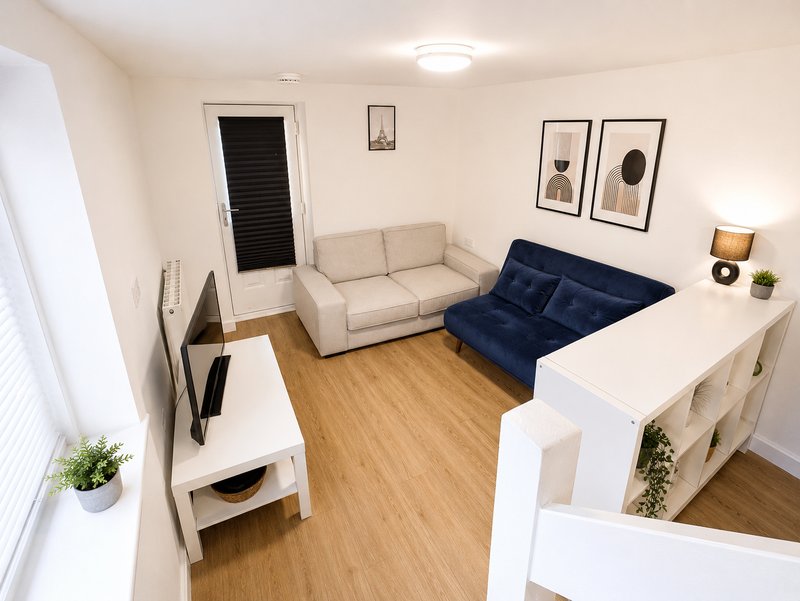 Modern living room with cream and navy sofas, wooden floor, wall art and desk area