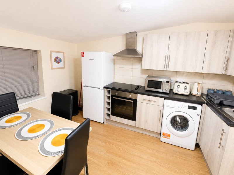 Modern kitchen with wooden cabinets, dining table, appliances and wooden flooring
