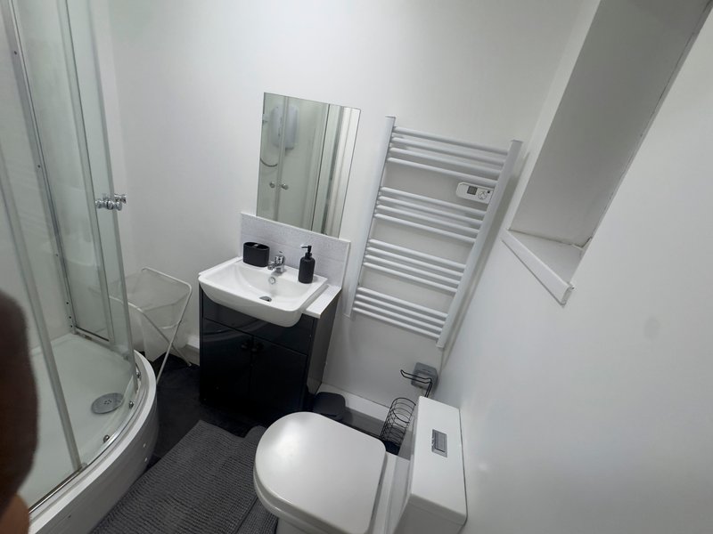 Modern bathroom with toilet, sink vanity, heated towel rack and shower enclosure