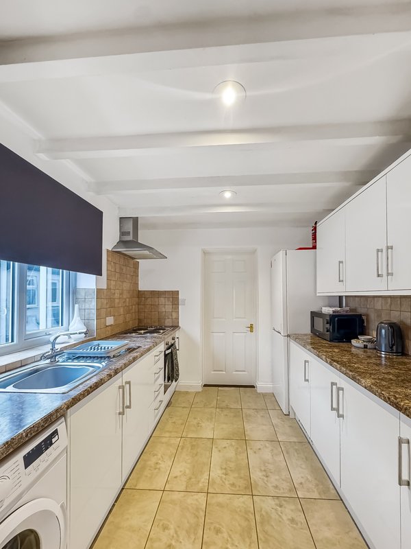 Modern galley kitchen with cream cabinets, granite counters, tiled floor and recessed lighting