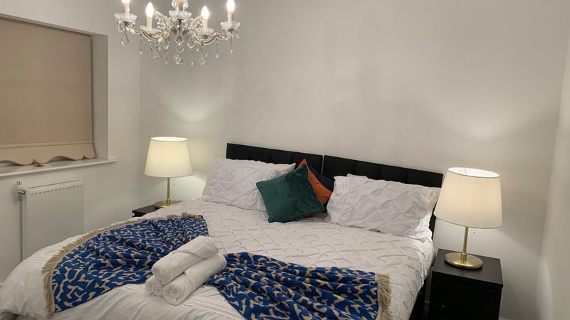 Bedroom with double bed, decorative pillows, bedside lamps, and crystal chandelier overhead