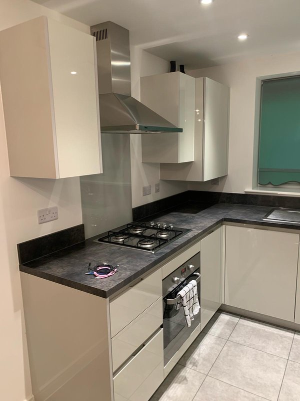 Modern kitchen with cream cabinets, black countertop, gas hob, and stainless steel extractor hood