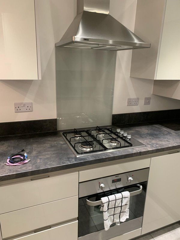 Modern kitchen with cream cabinets, gas hob, stainless steel extractor hood and dark countertop
