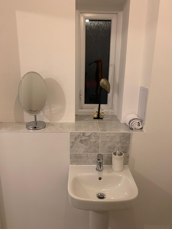 Bathroom sink with mirror, faucet, toiletries and window above