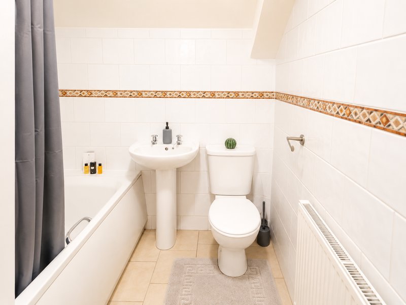 Small bathroom with pedestal sink, toilet, and decorative tile border
