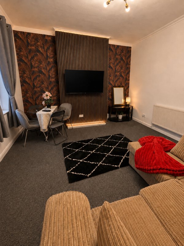 Modern living room with wall-mounted TV, patterned accent wall, geometric rug, and contemporary furnishings