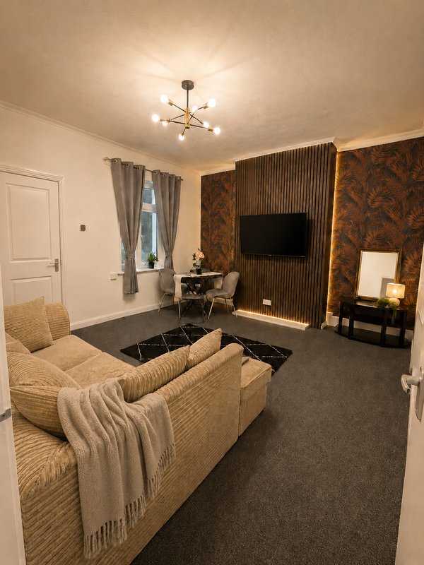 Cozy living room with beige sofa, wall-mounted TV, patterned accent wall, and ceiling light fixture