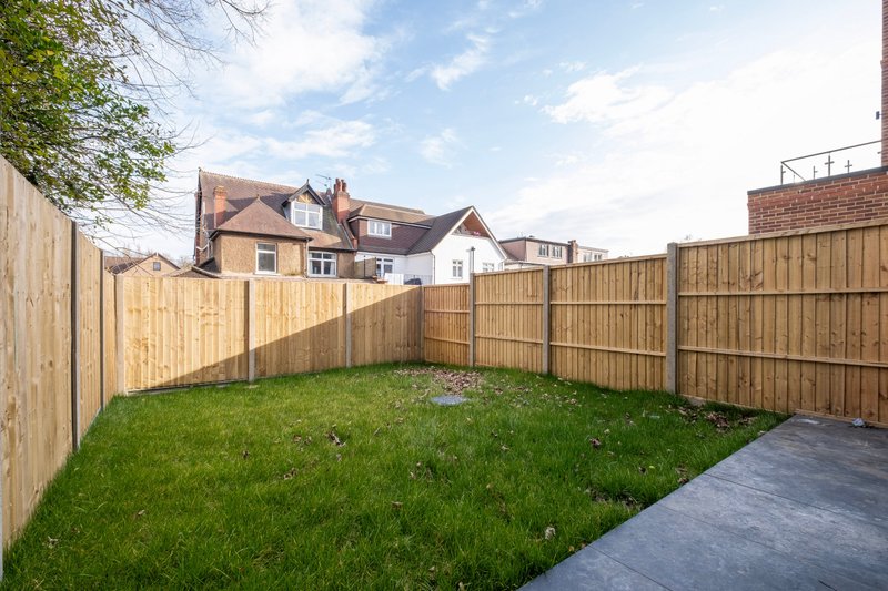 Enclosed garden with wooden fence, lawn area, and neighboring houses visible