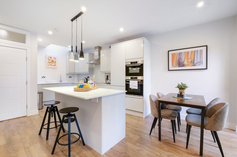 Modern open-plan kitchen and dining area with white cabinetry, island seating, and wooden dining table