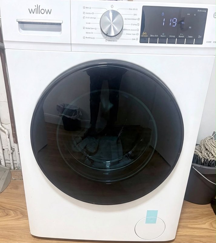 Modern white washing machine with dark drum and digital display in utility room