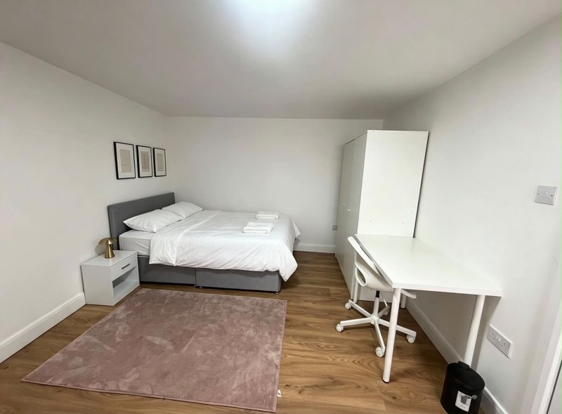 Bedroom with double bed, desk, chair, wardrobe and wooden flooring
