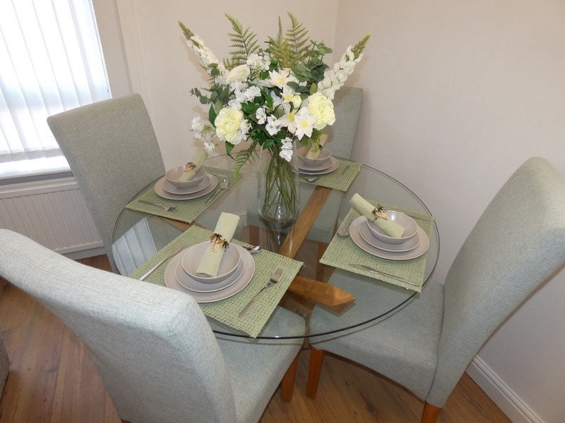 Dining table with place settings, floral centerpiece and four upholstered chairs