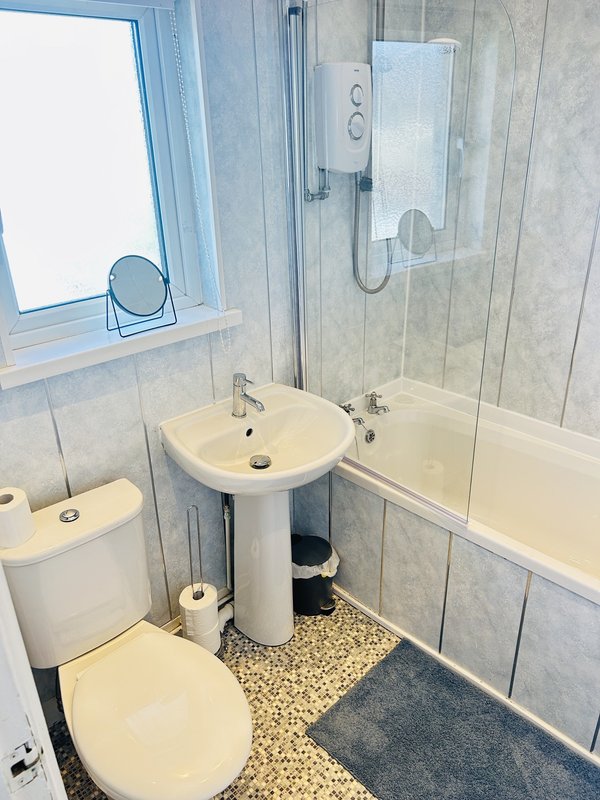 Modern bathroom with toilet, pedestal sink, shower enclosure and window
