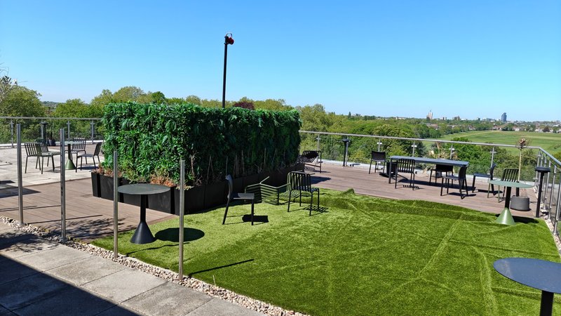 Spacious outdoor terrace with green lawn, dining tables, chairs and countryside views