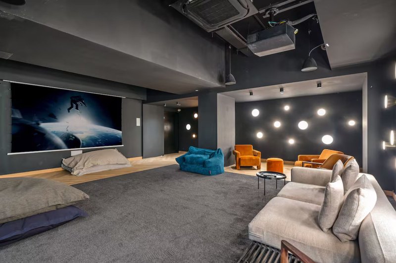 Modern media room with grey carpet, seating furniture, large screen and decorative lighting wall