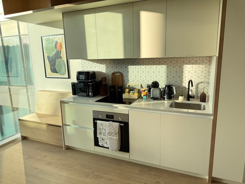 Modern kitchen with white cabinetry, geometric backsplash, built-in appliances and countertop accessories