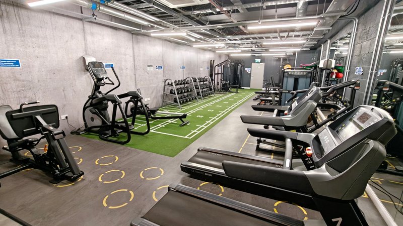 Modern gym facility with treadmills, exercise bikes, and green turf flooring