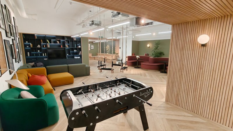 Open-plan living space with foosball table, colorful seating, and modern furnishings