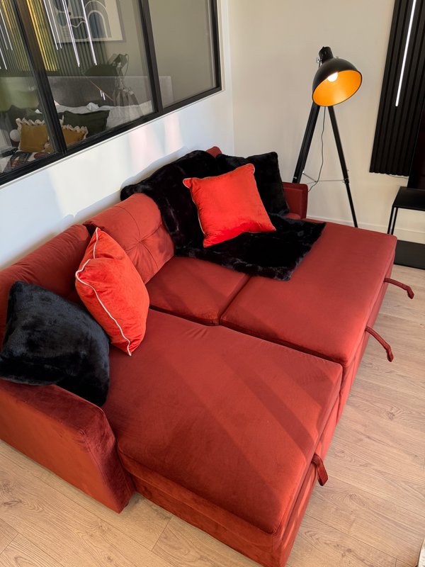 Modern living room with red sofa, black cushions, arched floor lamp and wooden floor