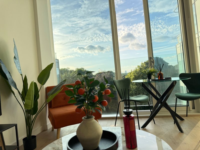 Modern living room with large windows, mountain view, flowers in vase, desk and seating