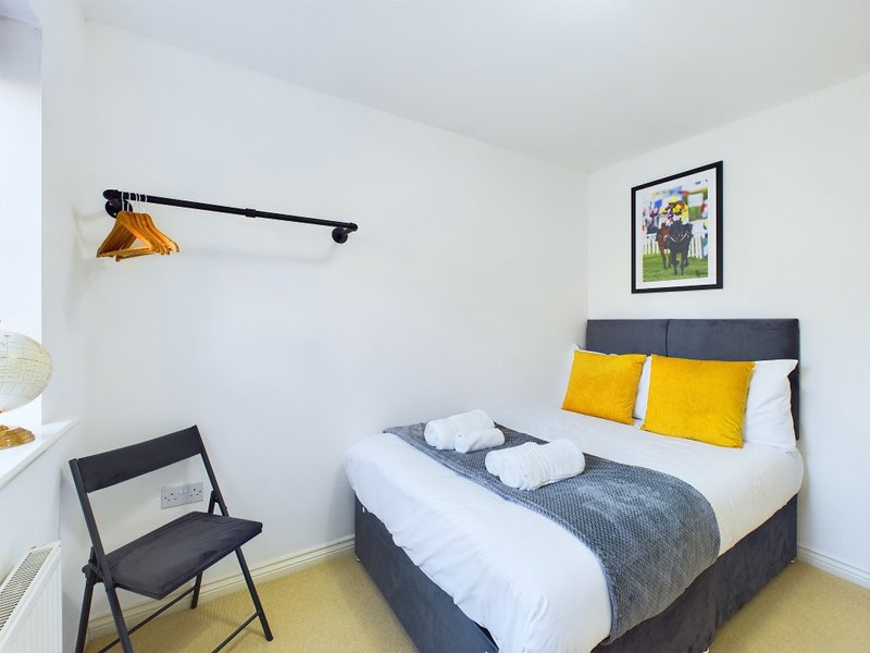 Modern bedroom with double bed, yellow pillows, black chair and wall-mounted lamp