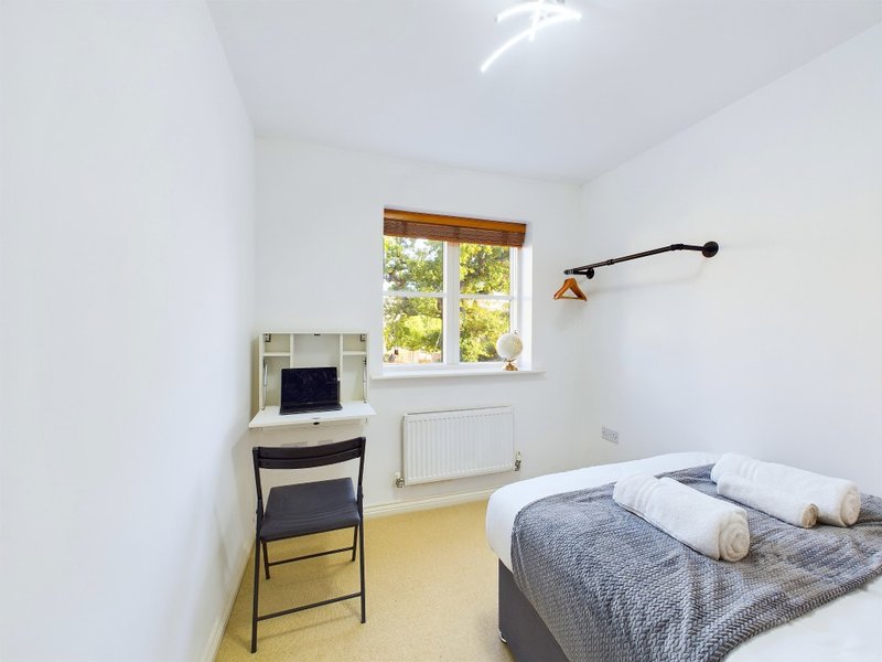 Bright bedroom with double bed, desk, chair, window and wall-mounted lamp