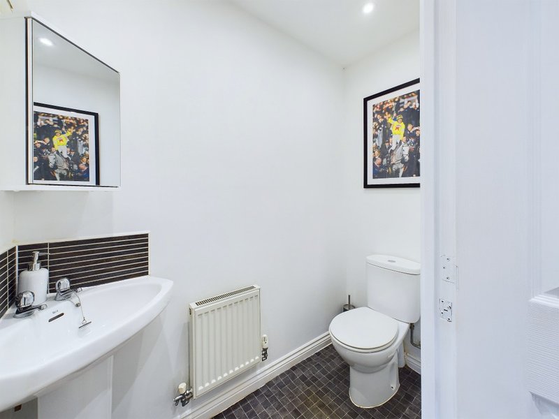 Modern bathroom with white pedestal sink, toilet, radiator and framed artwork