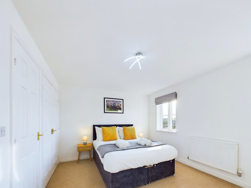 Bright bedroom with double bed, yellow cushions, wardrobe, small table and window