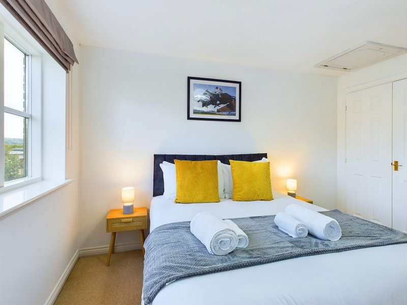 Bright bedroom with double bed, yellow pillows, rolled towels, and bedside lamps