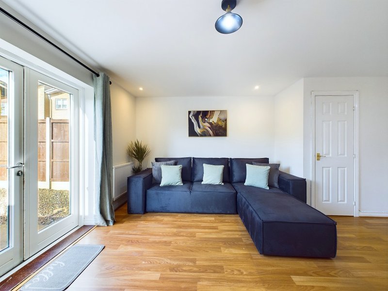 Modern living room with blue sectional sofa, wooden floor, and glass doors to garden