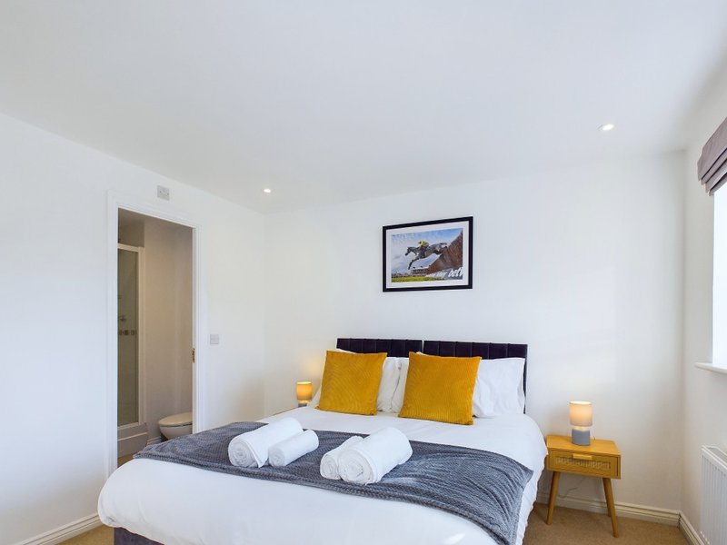 Modern bedroom with double bed, yellow cushions, white bedding, and wooden nightstands