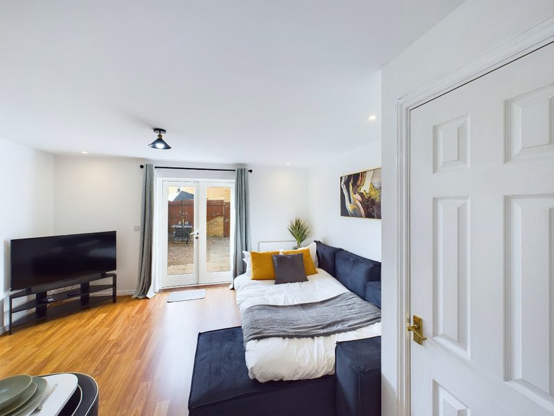 Bright studio bedroom with double bed, TV, wooden floors and patio doors