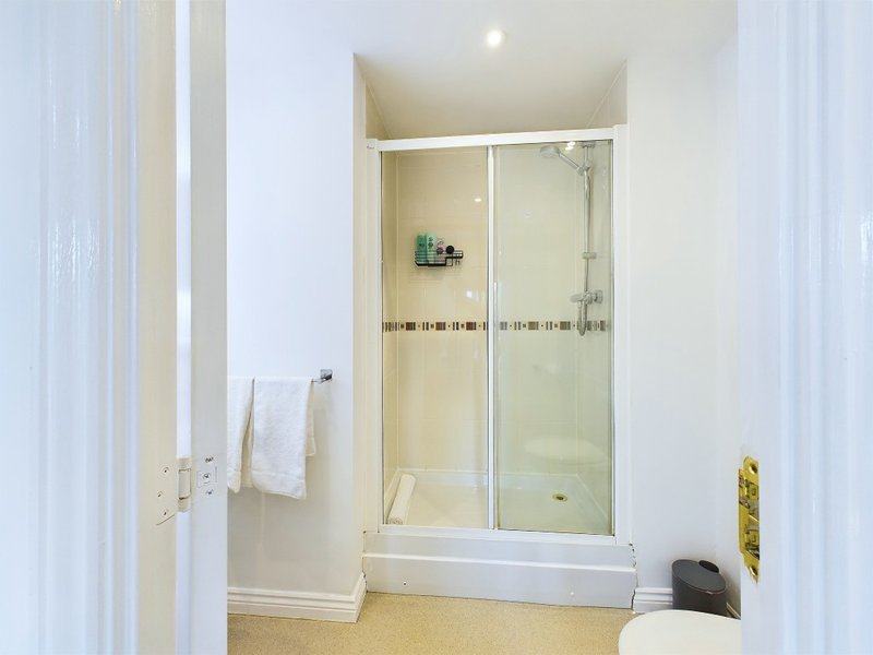 Modern bathroom with glass shower enclosure, white tiles, towel rail and toilet